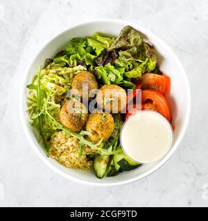 Falafel und frisches Gemüse gemischter Salat auf weißem Marmortisch Hintergrund, Draufsicht. Vegetarisch, Diät-Food-Konzept Stockfoto