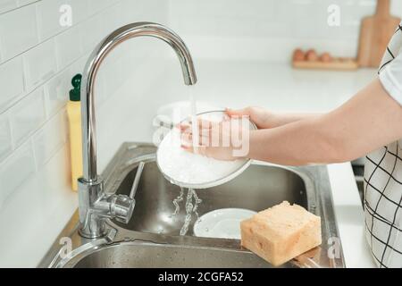 Frau Waschplatte in der modernen Küche, Nahaufnahme. Zugeschnittenes Bild von attraktiven jungen Frau ist Geschirr waschen, während die Reinigung zu Hause Stockfoto