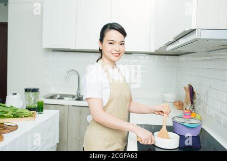 Junge Frau, die in der Nähe der Induktion Herd kochen Mahlzeit in der Küche Stockfoto