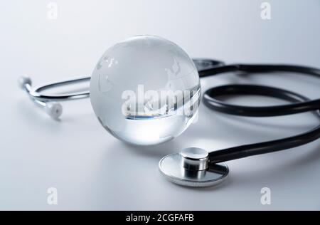 Ein Glasglobus und Stethoskop auf weißem Hintergrund. Stockfoto