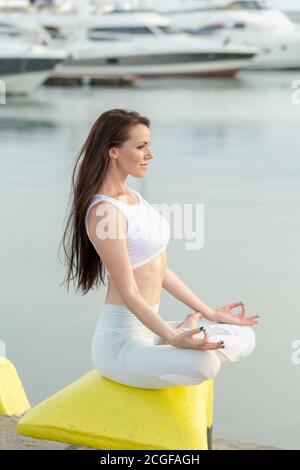 Seitenansicht des schönen Mädchen mit langen braunen Haaren im Sport Kleidung Entspannung auf See Dock nach frühen Workout, schließen Sie die Augen und atmen Sie langsam Whil Stockfoto