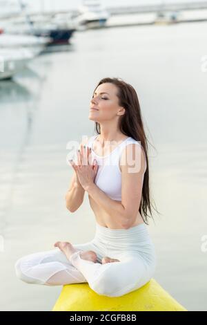 Seitenansicht des schönen Mädchen mit langen braunen Haaren im Sport Kleidung Entspannung auf See Dock nach frühen Workout, schließen Sie die Augen und atmen Sie langsam Whil Stockfoto