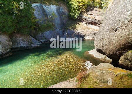 Sonniges Rückwasser des Bergflusses mit riesigem Felsen Stockfoto