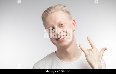 Positive Hipster Kerl zeigt Ziege oder Rock Zeichen, dämonstares, dass alles in Ordnung ist, und er hat einen freien Willen. Selbstbewusst fröhliche Mann Gesten drinnen. Bo Stockfoto