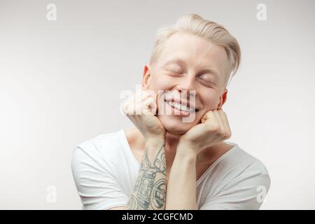 Hipster Kerl lehnt sich auf tätowierte Hände mit fröhlichen und glücklichen Ausdruck auf der Suche nach. Positive Emotionen Stockfoto