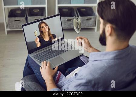 Online-Dating. Online-Treffen eines jungen Mannes und einer jungen Frau. Ein Mann nutzt einen Videoanruf, hält ein Glas Champagner und kommuniziert mit einer schönen Frau. Stockfoto