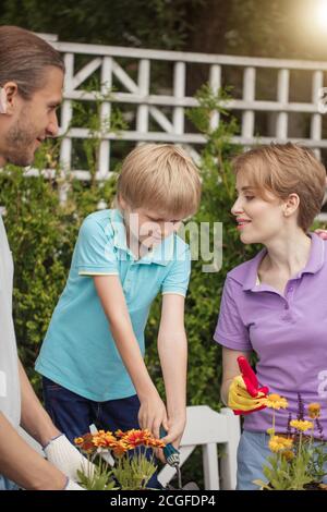 Junge Eltern hilft Blume Pflanzen im Topf. Gartenarbeit, Pflanzen Konzept - Eltern Blumen Pflanzen in kleine Töpfe Stockfoto