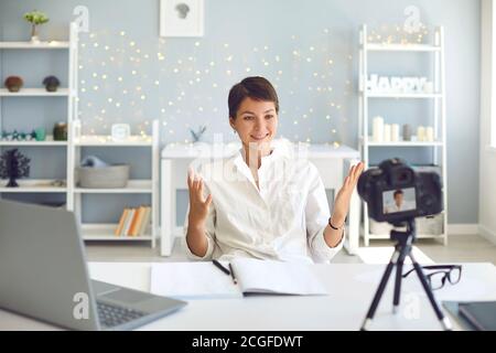 Fröhliche weibliche Vlogger Aufnahme eines Videos auf Kamera sitzen an Ihr Schreibtisch im Heimbüro Stockfoto