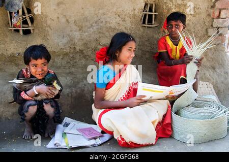 Joy of Learning - eine ältere Schwester lernen Englisch zu ihrer Schwester und kleinen Bruder vor ihrem Haus. In dem abgelegenen Dorf West Bengalen I Stockfoto