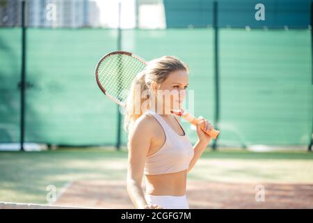 Erfolgreiche blonde Sportlerin mit Schläger auf dem Tennisplatz mit Copyspace. Gesunder Lebensstil. Konzept von Sport Victory und Tennis. Stockfoto