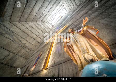 Blick auf den Kamin-ähnlichen Turm, vom Altar, Kruzifix und Statue von Jesus, zu einem hohen Fenster Licht, atemberaubende brutalistischen kommunistischen Ära Design, com Stockfoto