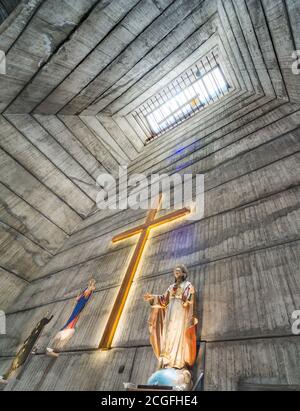 Blick auf den Kamin-ähnlichen Turm, vom Altar, Kruzifix und Statue von Jesus, zu einem hohen Fenster Licht, atemberaubende brutalistischen kommunistischen Ära Design, com Stockfoto