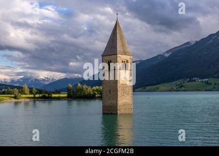 Der berühmte Glockenturm des alten Graun, untergetaucht im Reschensee, Südtirol, Italien, mit den schneebedeckten Alpen im Hintergrund Stockfoto