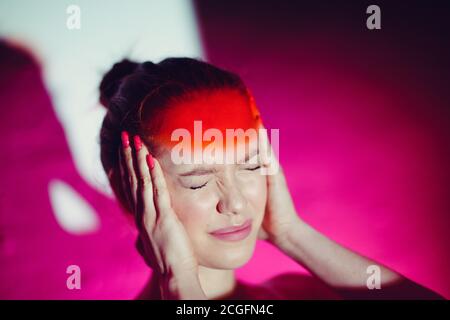 Junge Frau mit Kopfschmerzen und roter Stirn Stockfoto