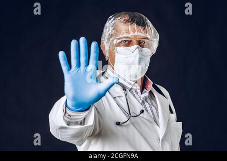Arzt mit Stoppschild, medizinische Maske und Handschuhe. Stockfoto