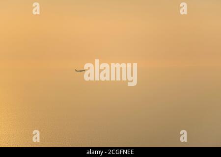 Das Flugzeug klettert, fliegt über das Meer in Richtung Sonne bei Sonnenuntergang Stockfoto