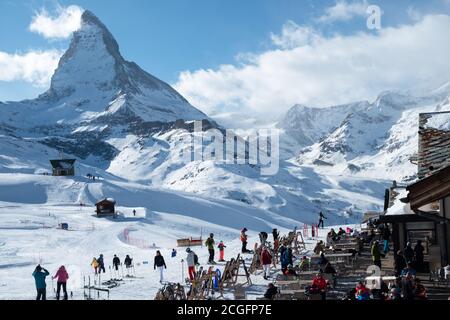 Zermatt, Schweiz - Feb 19 2020: Skifahrer im Schnee vor einem Restaurant mit Blick auf das Matterhorn. Stockfoto