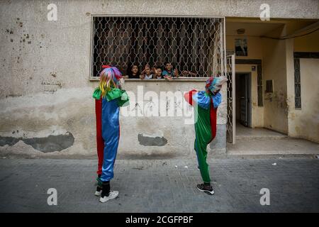 Gaza, Palästina. September 2020. Palästinensische Jugendliche, die als Clowns gekleidet waren und Gesichtsmasken trugen, inszenierten als vorbeugende Maßnahme eine Straßenvorstellung, um Kinder zu unterhalten, die zu Hause aufgrund des Coronavirus-Ausbruchs in Khan Yunis im südlichen Gazastreifen gefangen waren. Kredit: SOPA Images Limited/Alamy Live Nachrichten Stockfoto