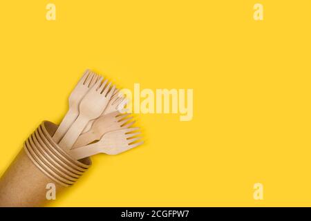 Holzgabeln in Einwegbechern und auf gelbem Hintergrund Mit Kopierbereich Stockfoto