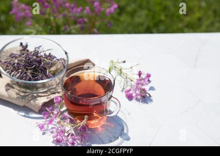 Chamaenerion Angustifolium Tee (Zypresse, große Weide, rosa Weide) mit trockenen und frischen Blumen zur Dekoration in Glas Tassen auf einem hellen Hintergrund. Konz Stockfoto