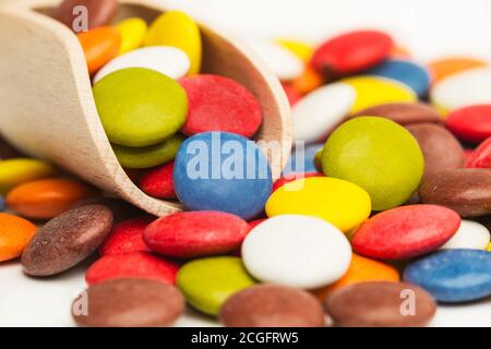 Bunte Hartschalenschokolade Bonbons mit einer Holzlöffel in Eine Nahaufnahme Stockfoto