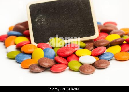 Bunte Hartschalenschokolade Bonbons mit einer leeren kleinen Tafel Stockfoto