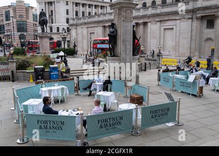 Diners und Trinker sitzen auf Straßensperren, wo Fortnum & Masons während der Coronavirus-Pandemie am 9. September 2020 in London, England, ein Restaurant und eine Bar im Freien vor der Royal Exchange at Bank in der City of London eingerichtet haben. Stockfoto