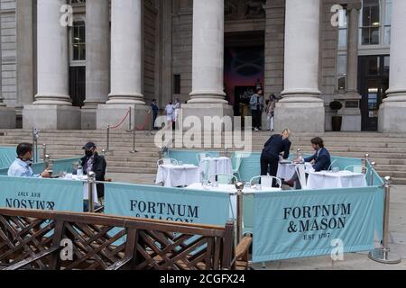 Diners und Trinker sitzen auf Straßensperren, wo Fortnum & Masons während der Coronavirus-Pandemie am 9. September 2020 in London, England, ein Restaurant und eine Bar im Freien vor der Royal Exchange at Bank in der City of London eingerichtet haben. Stockfoto