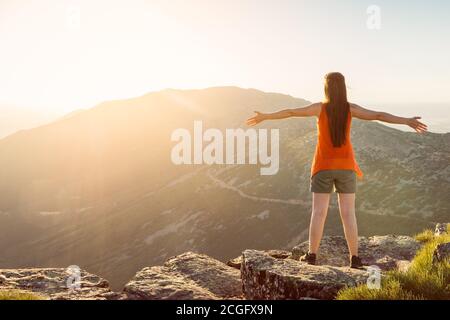 Glückliche Frau mit offenen Armen bleiben auf dem Gipfel der Die Bergklippe Rand unter Sonnenuntergang Licht Stockfoto