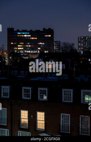 Ein Blick aus einer Wohnung über London bei Nacht mit Fensterrückstellungen und Leuchten, die draußen im Dunkeln leuchten. Stockfoto