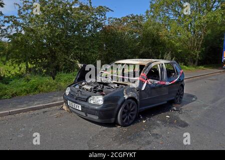 Ein ausgebrannter Volkswagen Golf, der Feuer mit Feuer und Rescure Service Barriere Band gefangen hat, in einem Layby in Telford, Shropshire Stockfoto