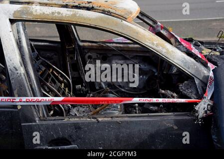 Ein ausgebrannter Volkswagen Golf, der Feuer mit Feuer und Rescure Service Barriere Band gefangen hat, in einem Layby in Telford, Shropshire Stockfoto