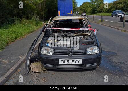 Ein ausgebrannter Volkswagen Golf, der Feuer mit Feuer und Rescure Service Barriere Band gefangen hat, in einem Layby in Telford, Shropshire Stockfoto