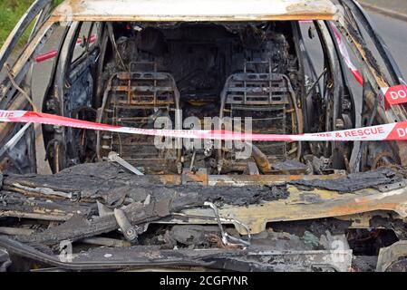 Ein ausgebrannter Volkswagen Golf, der Feuer mit Feuer und Rescure Service Barriere Band gefangen hat, in einem Layby in Telford, Shropshire Stockfoto