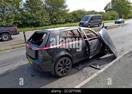 Ein ausgebrannter Volkswagen Golf, der Feuer mit Feuer und Rescure Service Barriere Band gefangen hat, in einem Layby in Telford, Shropshire Stockfoto