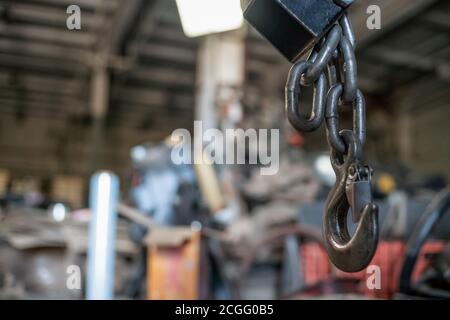 Leistungsstarker Kranhaken aus nächster Nähe. Vor dem Hintergrund einer Industrieanlage. Industrieller Hintergrund. Stockfoto