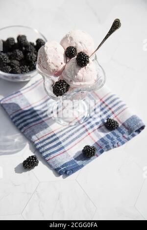 Eine Schüssel mit Eis und Brombeeren sitzt auf einer blau karierten Serviette. Nahaufnahme.Vertikale Ausrichtung. Stockfoto