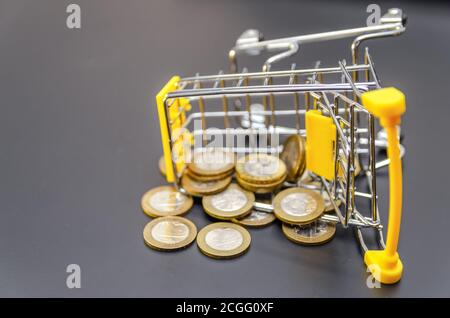 Goldmünzen aus einem gelben Warenkorb auf einem verstreut Nahaufnahme mit schwarzem Hintergrund Stockfoto