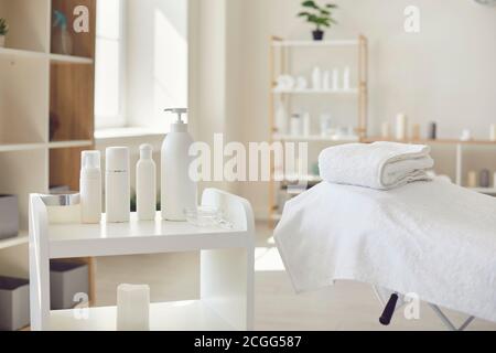 Spa-Raum oder Schönheitssalon mit Set von Bio-Hautpflege Produkte und leeres Bett mit frischen Handtüchern Stockfoto