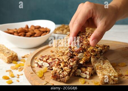 Weibliche Hand halten Müsliriegel auf Holzhintergrund mit Müsli Balken Stockfoto