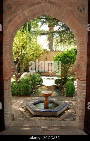 Blick durch einen maurischen Torbogen zum Brunnen und Garten im Garten des Mondragon Palace, Ronda, Provinz Malaga, Spanien. Stockfoto