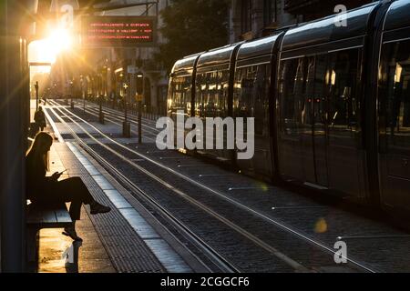 Bordeaux, Frankreich - 24. September 2018: Frau wartet auf die Straßenbahn in der Innenstadt von Bordeaux bei Sonnenuntergang. Stockfoto