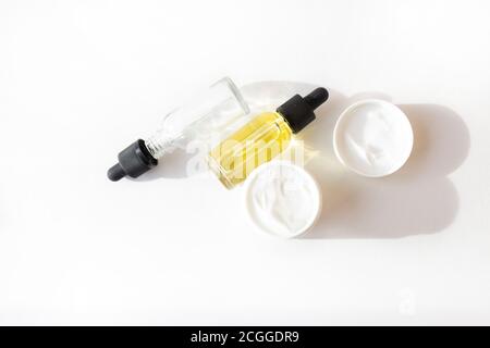 Tropfen Flasche mit Öl, Sahne in einem weißen Glas. Hautpflegekonzept Stockfoto