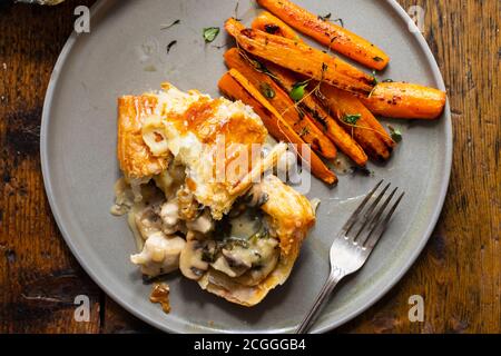 Hühnchen- und Pilzkuchen mit gebratenen Karotten Stockfoto