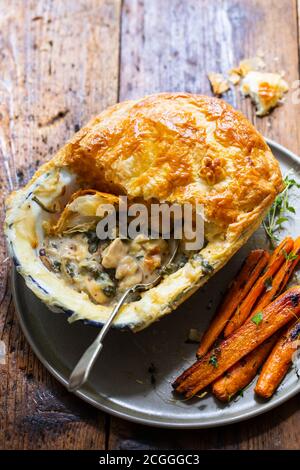 Hühnchen- und Pilzkuchen mit gebratenen Karotten Stockfoto