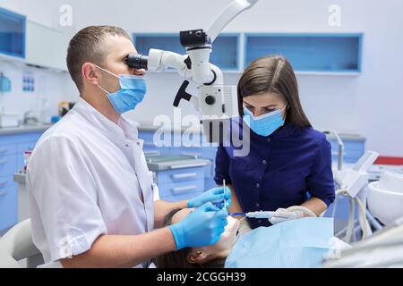 Männlich Arzt Zahnarzt Behandlung von Zähnen mit zahnmedizinischen Mikroskop-Instrumente Stockfoto
