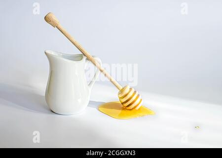 Kanne Sahne zum Frühstück. Honigstock mit fließendem Nektar auf weißem Tisch Stockfoto