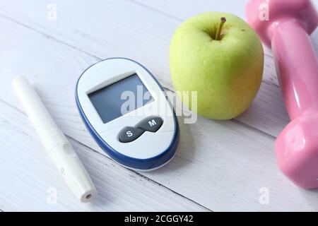 Nahaufnahme von diabetischen Messgeräten, Apfel und Hantel auf dem Tisch Stockfoto