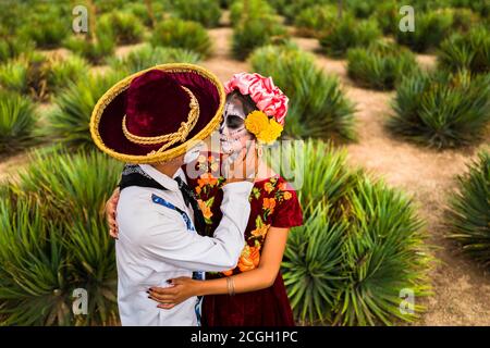 Ein junges mexikanisches Paar, beide als La Catrina gekleidet, umarmt sich während der Feierlichkeiten zum Tag der Toten in Oaxaca, Mexiko. Stockfoto