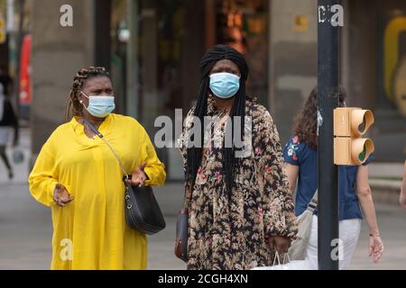 Zaragoza, Spanien - 18. August 2020: Ein paar schwarze inmigrantische Frauen, die aufgrund der Coronavirus-Pandemie mit Gesichtsmasken im zentralen Bereich von Za sprechen Stockfoto